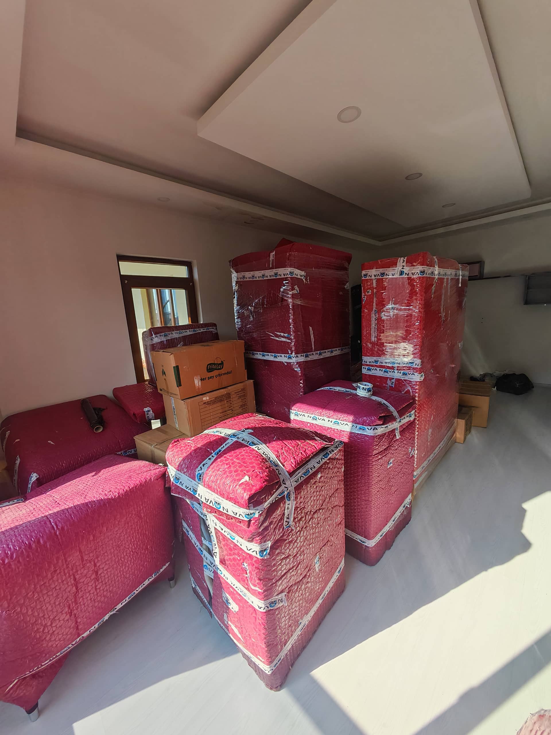 Taşıma öncesi kırmızı koruyucu battaniyelerle paketlenen ev eşyaları